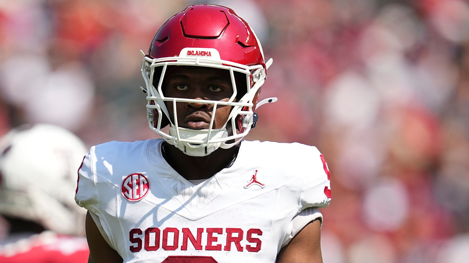 Oklahoma WR Keontez Lewis Injured After Hitting Head on B... 1 A football player in a white Oklahoma Sooners uniform and red helmet on the field.